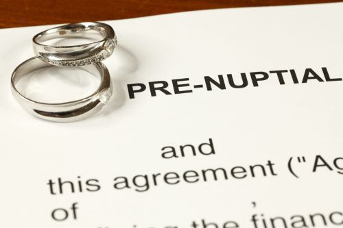 Close up of wedding rings sitting on prenuptial agreement - What to include in prenuptial agreement concept