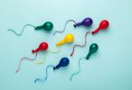 Colorful balloons in spermatozoid shape on blue background - friend as sperm donor concept