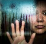 Depressed woman looking out of rainy window - Domestic violence concept