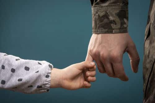 A soldier's hand holds a child's hand in close-up. My father is a military man. A soldier and a child. Father's love