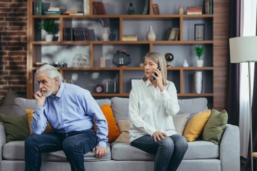 senior married couple quarreling while sitting on a couch - gray divorce concept