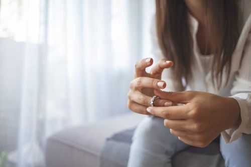 Unhappy woman holding wedding ring close up - divorce mistakes concept