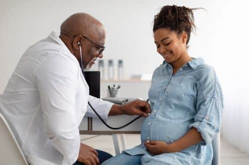 Smiling pregnant woman visiting her obstetrician - surrogacy insurance concept