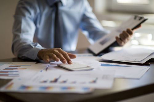 business man sitting at desk looking at financial documents with calculator - Forensic accountant divorce concept