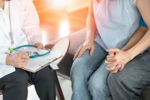 A couple holding hands speaking with a fertility doctor