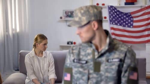 sad woman sits on the couch while military husband leaves