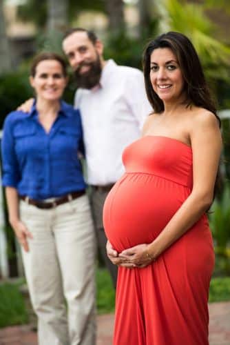 Pregnant surrogate mother posing with the babies future parents