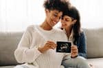 Same-sex pregnant couple holding up their ultrasound scan, parental rights concept
