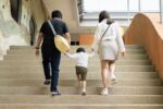 Back view of happy family walking up the stairs.