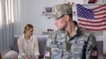 sad woman sits on the couch while military husband leaves